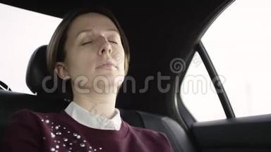 穿着白色衬衫和栗色毛衣的棕色头发的漂亮女人坐在车里，坐在车里，睡着了
